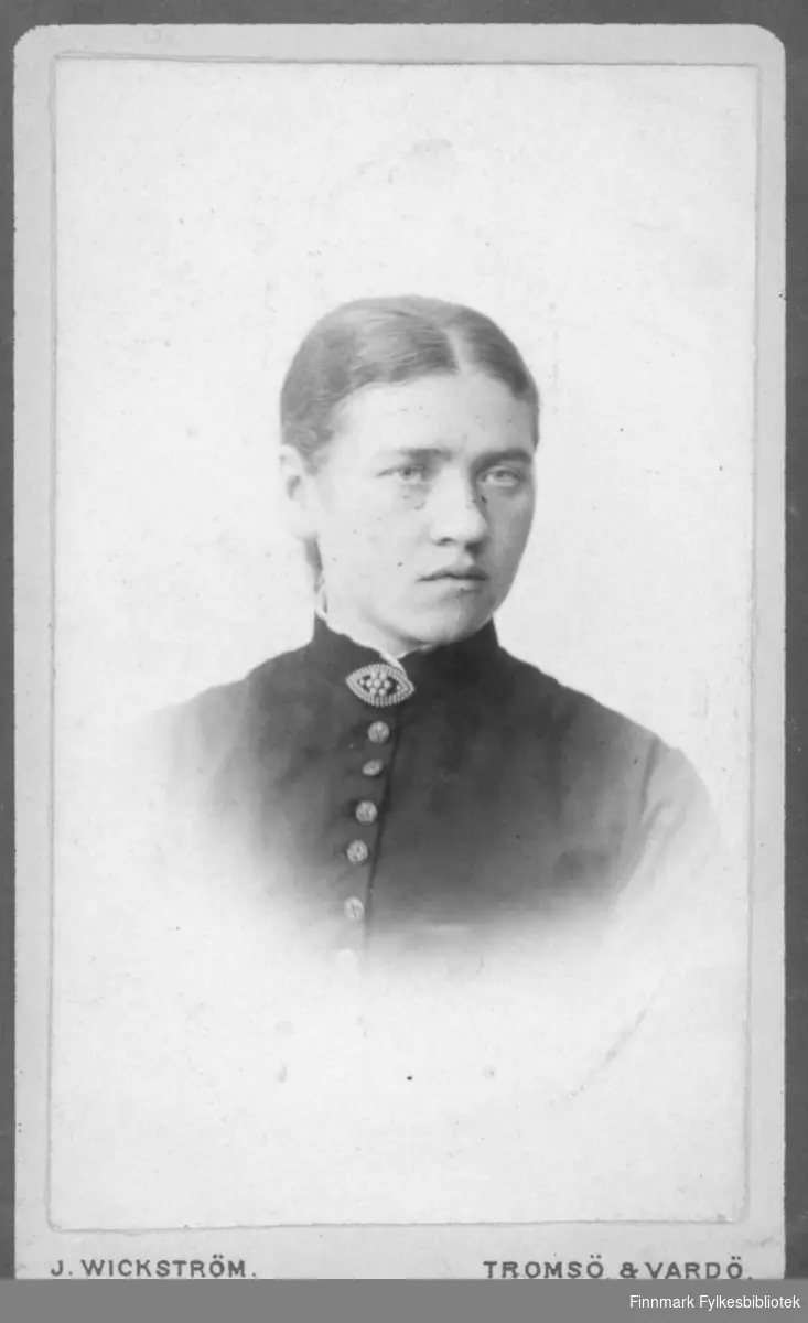 Halvfigur portrett av ei dame i Studio ateliere, hun har på seg en sort jakke med høy krage og brosje i halsen. Albumet med bildet kommer fra Ekkerøy, kanskje hun bodde der.
