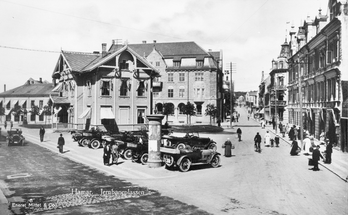 Postkort, Hamar. Jernbaneplassen med Hamars første stajonsbygning, ble flyttet i 1924, Torggata. Folk, biler. 