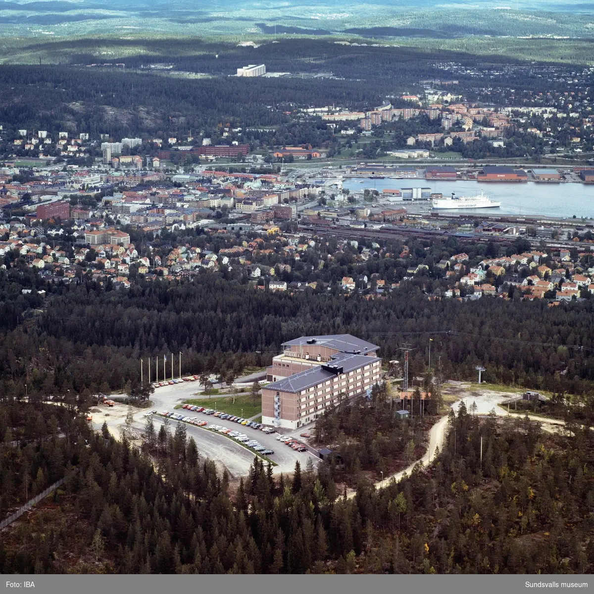 Flygbild över Sundsvallsbukten med Södra bergets hotellanläggning i förgrunden. I hamnen ligger en finlandsfärja.