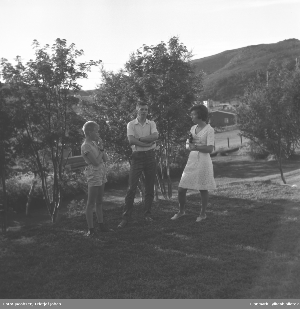 Tre personer står i hagen til Arne Nakken i Rypefjord. De er fra venstre: Sigmund Nakken, Øystein Nakken og Synnøve Nakken. Øystein er far til Sigmund og onkel til Synnøve.