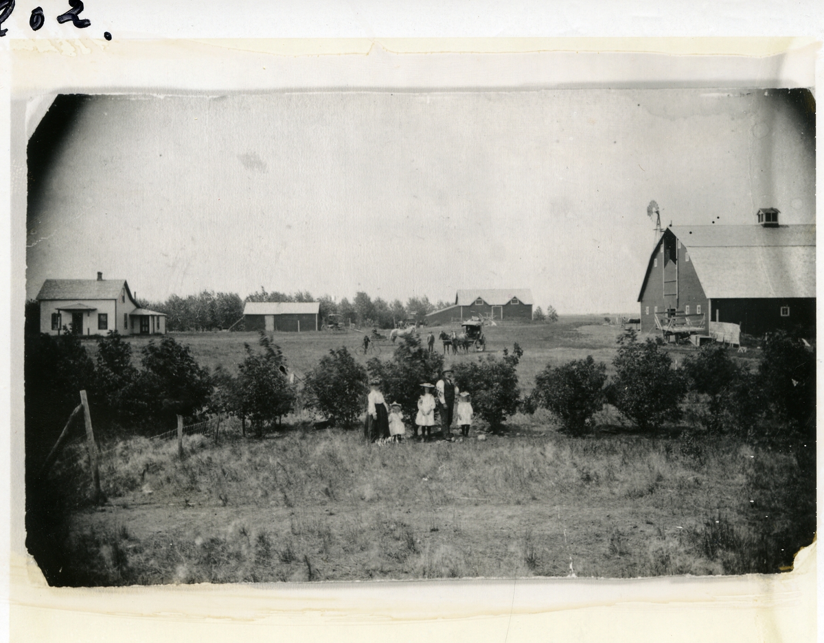 Bildet viser farmen til C. Melby i USA. Født ca 1850. Kona var fra Stokkebryn i Skrautvål. Familien foran og gårdshusene i bakgrunnen. Her er også flere hester og karjoler og en sykkel.
