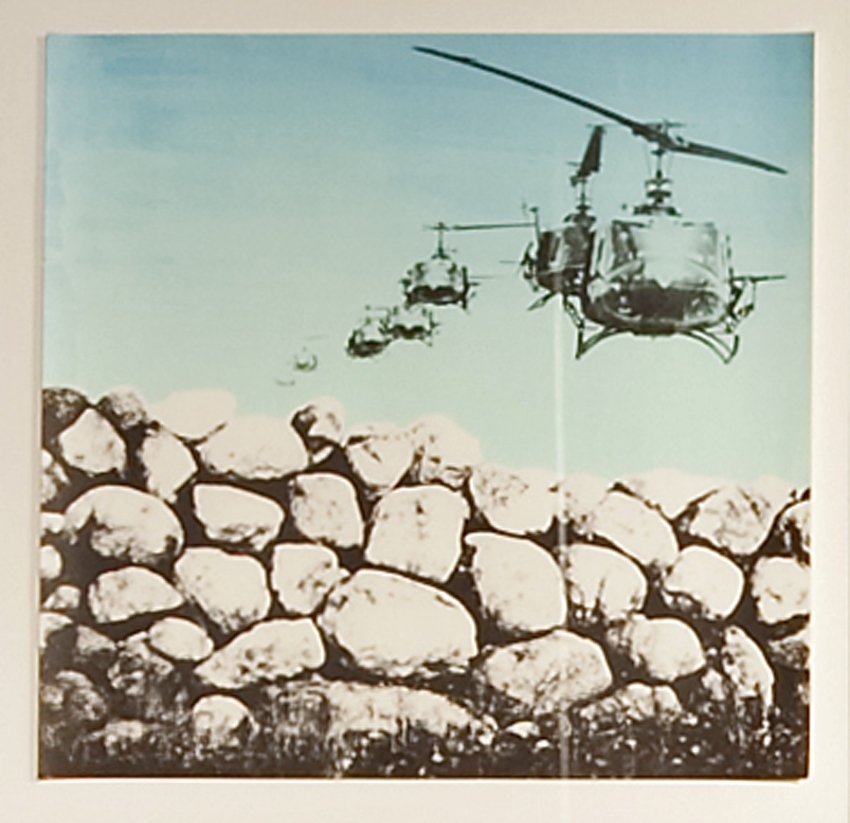 Motivet viser stridshelikoptre som flyr over en steinmur.