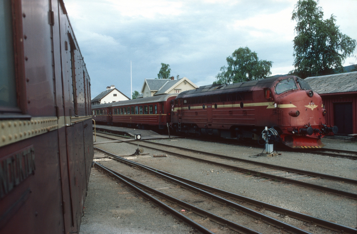 Persontog 283 fra Oslo S har ankommet Fagernes med dieselelektrisk lokomotiv Di 3 631. Lokomotivet skal skiftes over til godstog 5182, og konduktørvognen til godstoget synes i forgrunnen.