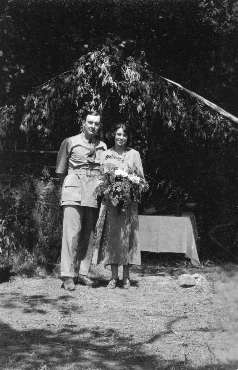 Brudeparet Marentius Thams (Ma) og Lydia Cherry står foran en løvhytte.