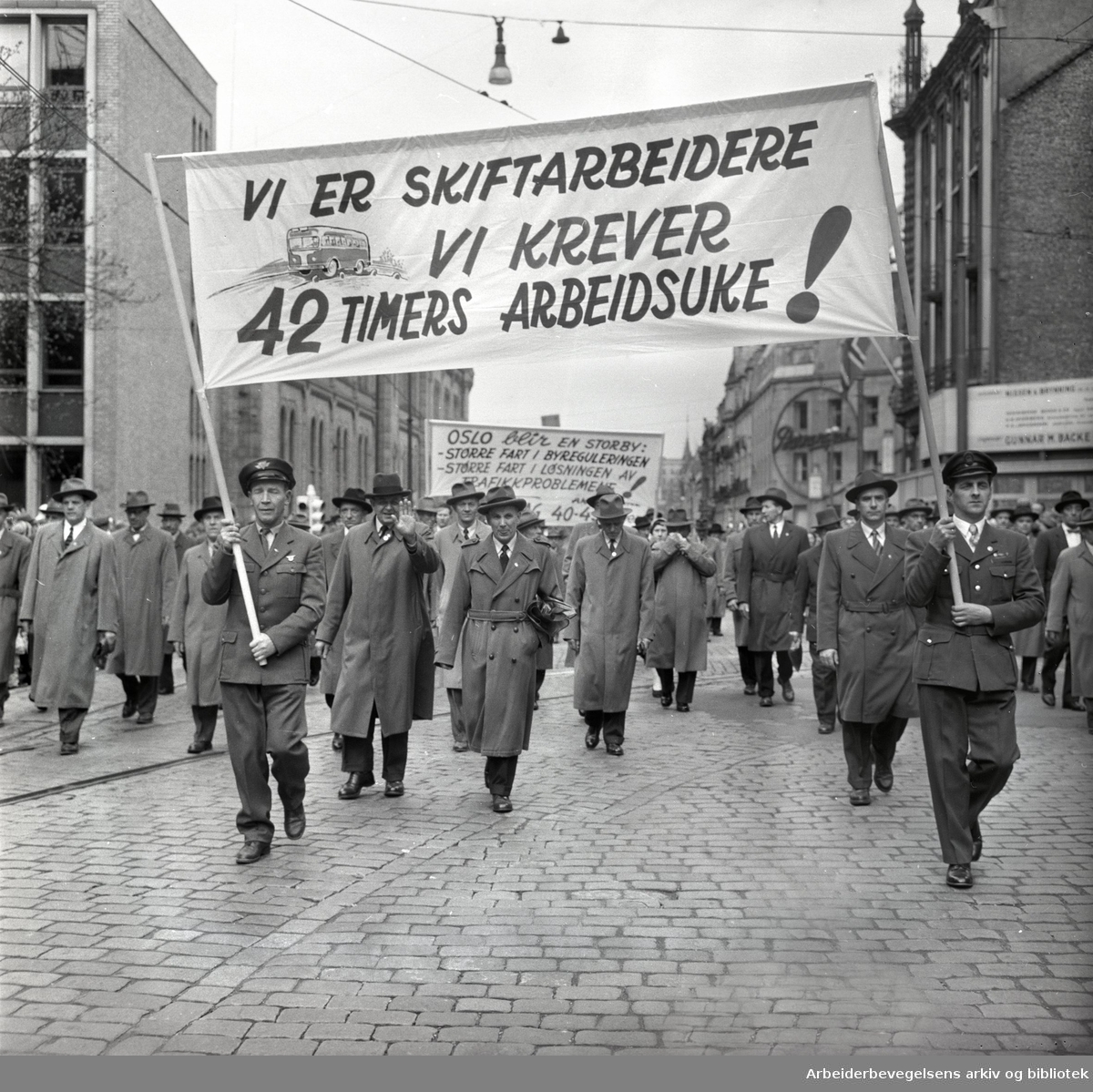 1. mai 1959 i Oslo.Karl Johans gate .Demonstrasjonstoget..Parole: Vi er skiftarbeidere.Vi krever 42 timers arbeidsuke!....