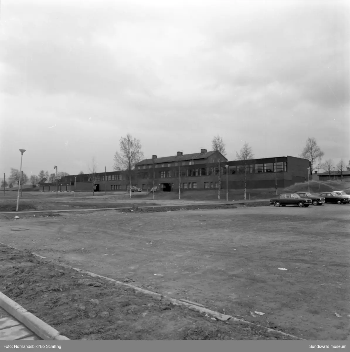 Exteriörbild av Högoms skola, norra sidan med den gamla skolbyggnaden bakom och längst till vänste skymtar gravkullarna.