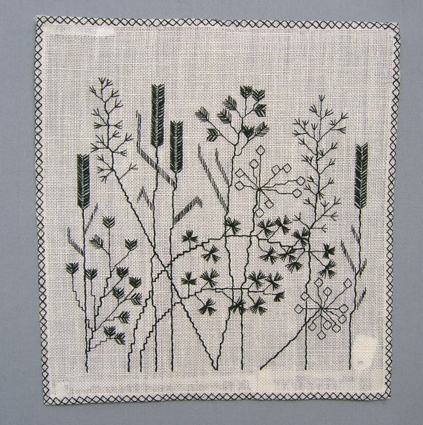 Väggprydnad GRÄS i form av broderad bild på vitt linne.Bilden föreställer olika sorters grässtrån. Broderat med svart lingarn i rutsöm, rätlinjig plattsöm och dubbla förtygn.