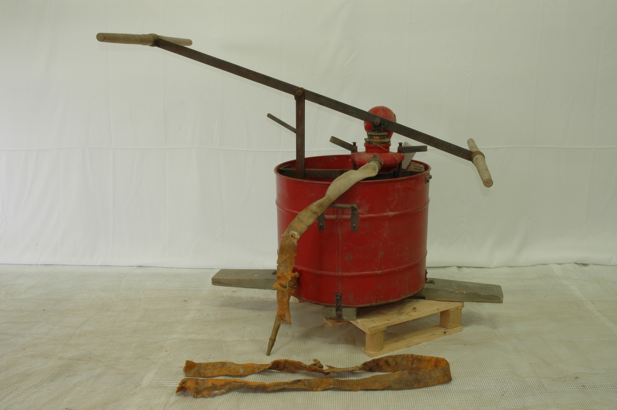 Rød vanntønne med pumpe og slange for brannslukking