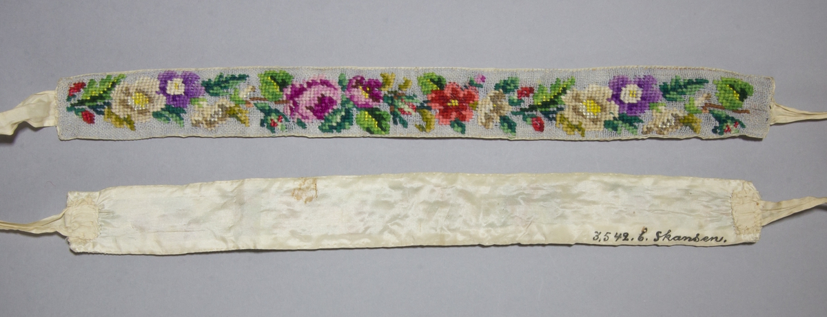Strumpeband för dam, ett par med rosenmönster, korsstygn av ullgarn på stramalj. Vissa detaljer sydda i silke. Baksida av sidentaft, vita sidenband fastsydda på kortsidorna.