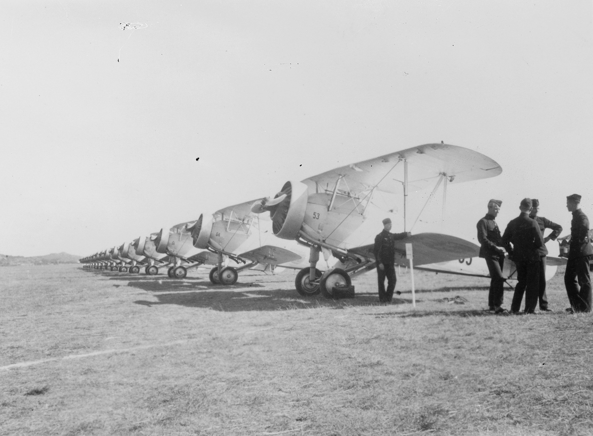 Flygplan B 4 Hawker Hart uppställda på linje på flygfält, cirka 16 stycken. Militärer vid flygplanen. Två av flygplanen märkta F4-53 samt F4-54.