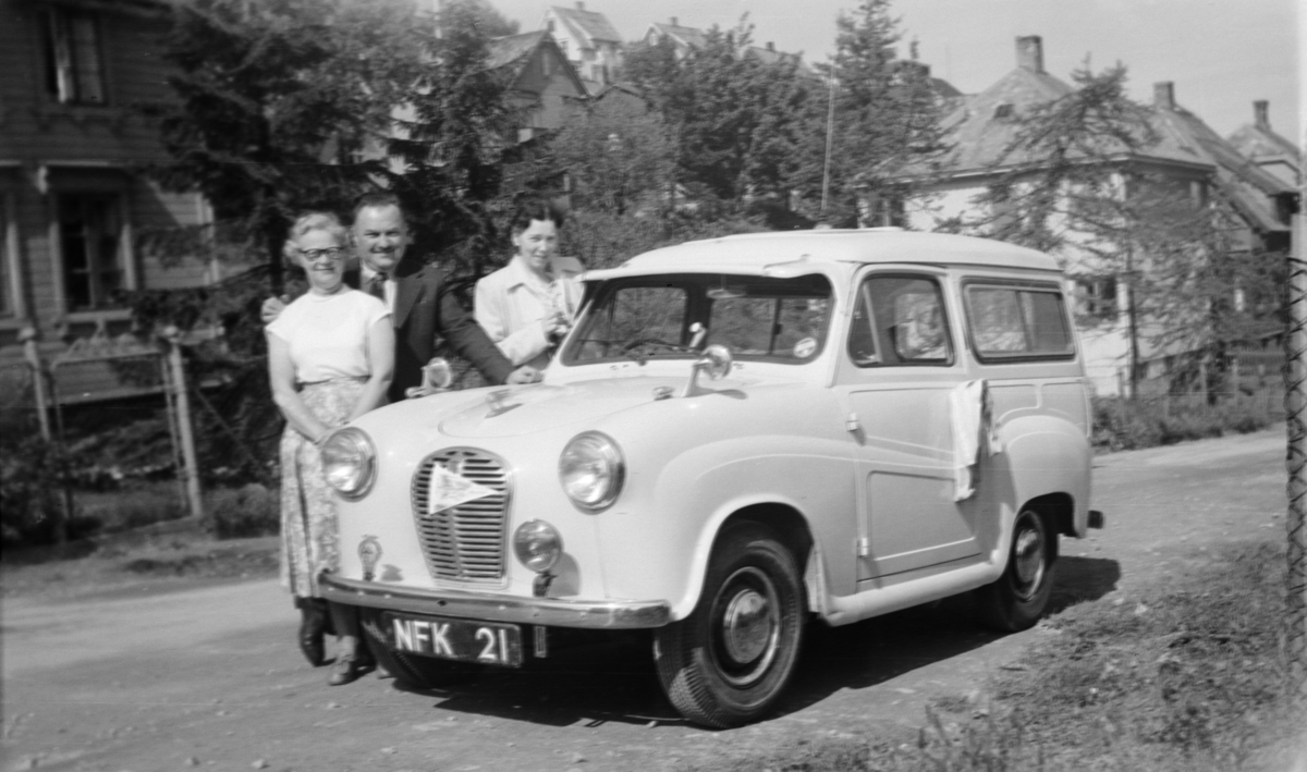 To kvinner og en mann ved en engelskregistrert bil.
