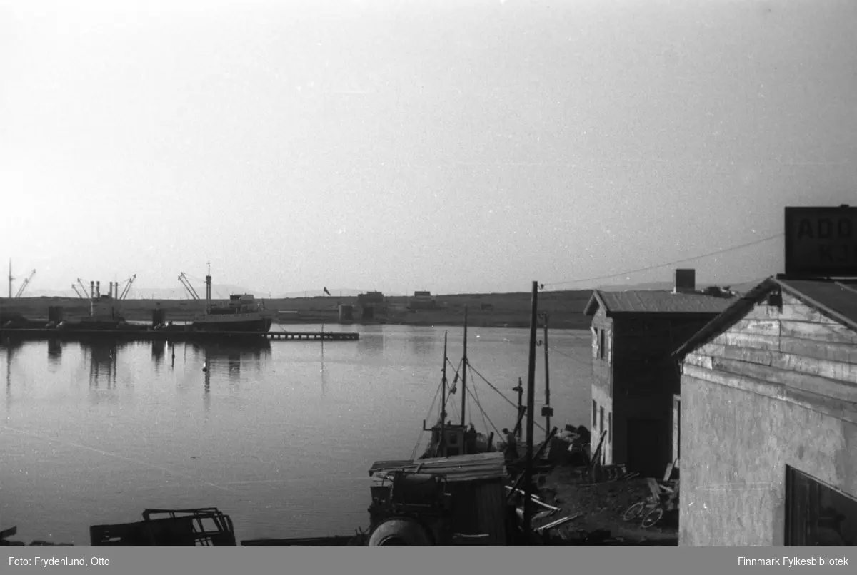 Havnemiljø i Vadsø. Fotografen har stått i nærheten av Samvirkekaia og har fått med havnebygninger, dampskipskaia og nyreiste bygninger på Vadsøya