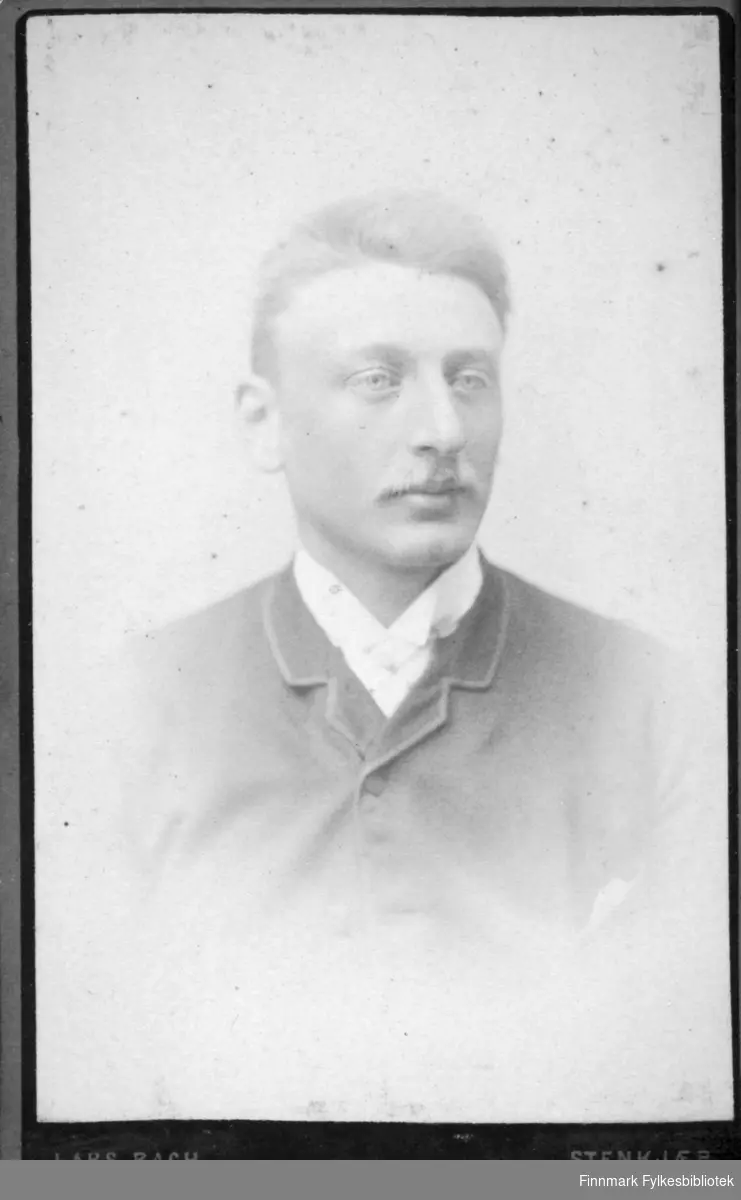 Portrett av en mann iført en ganske mørk jakke  med hvit skjorte under.
