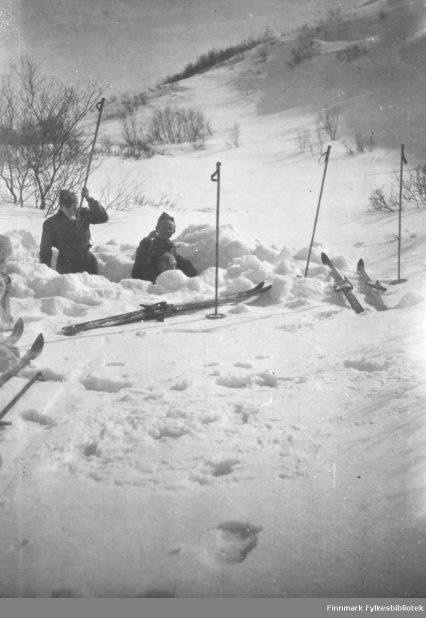Oppe i Thomaselv dalen. Vi drikker vann ved å ha sne på skistaven og så suge i oss dette. Per Bjørgan og Ernst Lebesby nede i hullet. Huene vi gikk med var gamle sveitsiske militærluer vi fikk etter en utdeling av klær innsamlet i Sveits.