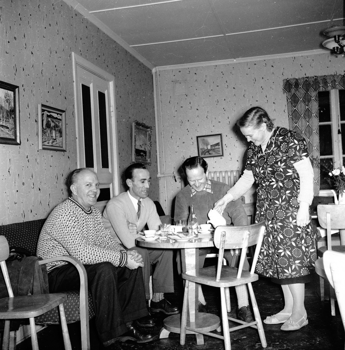 Sture, Evert Andersson och Kalle är i Rogberga och fikar. De blir serverade av Ulla Berg som hade konditoriet.