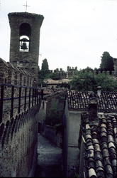 Foto av et klokketårn over trange smug. Muligens i Italia..