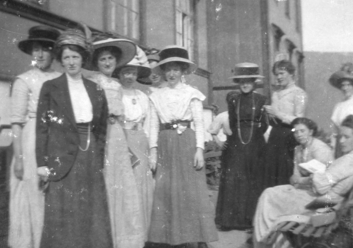 Utenfor lærerskolen, Tromsø. De unge kvinnene er kledd i kjole, jakke og hatt. enkelte har pyntet seg med smykker.
