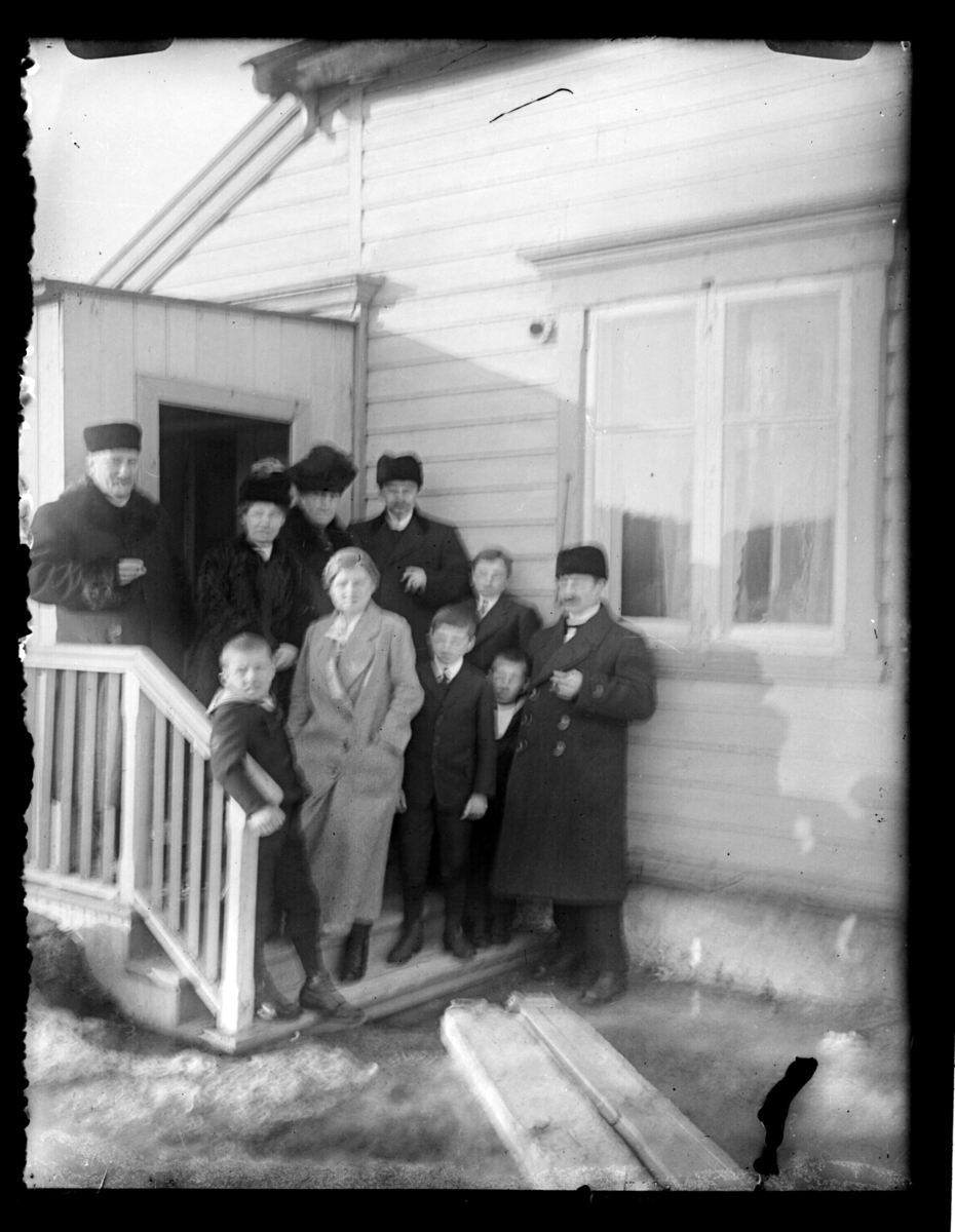 Et gruppebilde på en trapp. En kvinne, flere menn og noen barn.