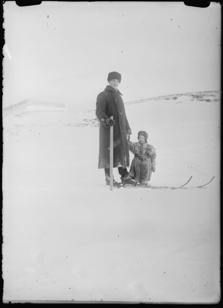 Vinter i Vardø. Mann med ski på beina, et barn i pesk.