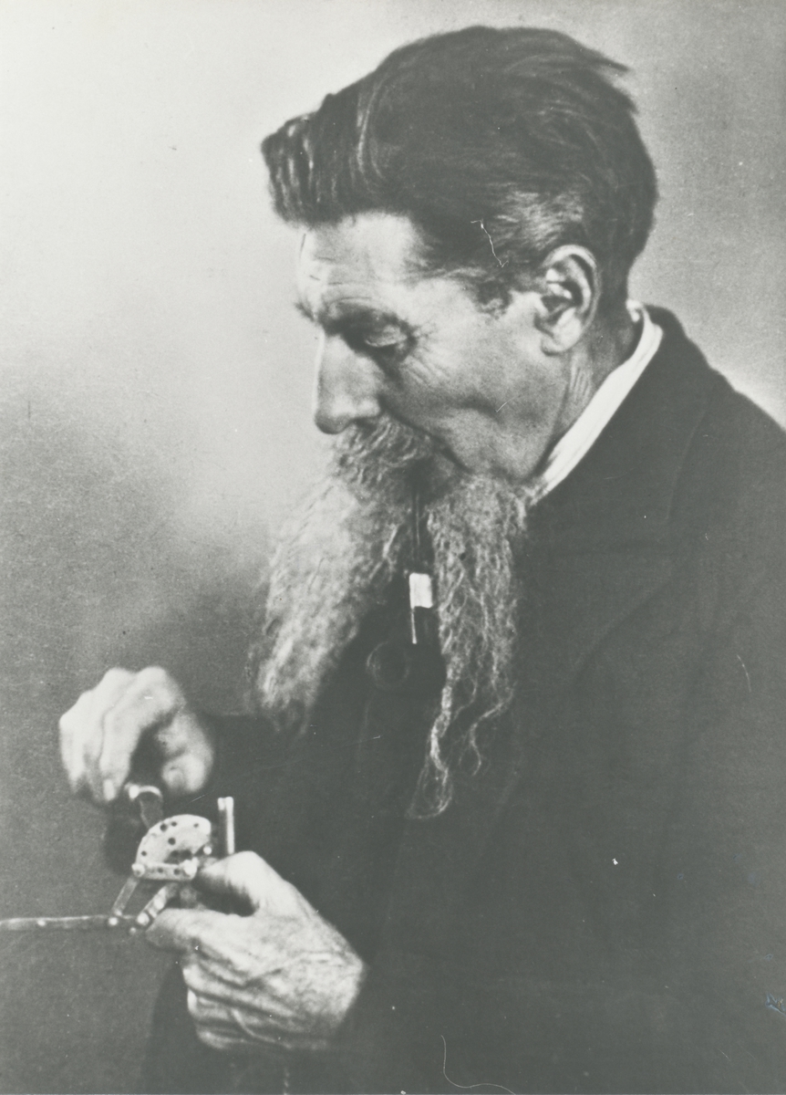Portrett av en mann som finstiller et instrument/ apparat.
