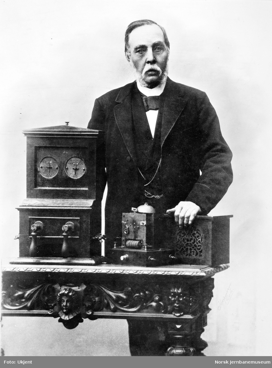 Telegrafinspektør Chr. Wiger med (fra v) Cooke & Wheatstones nåletelegraf, mottakerapparat for signaltelegrafen og en alarmklokke