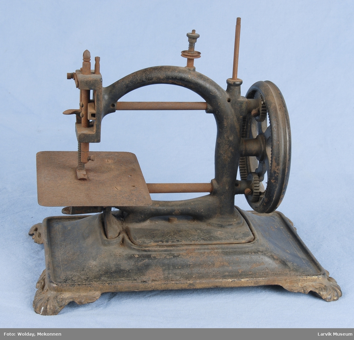 Form: maskinen står på en plate av jern med 4 føtter med skjelldekor/sveiv av tre/2 tannhjul av messing