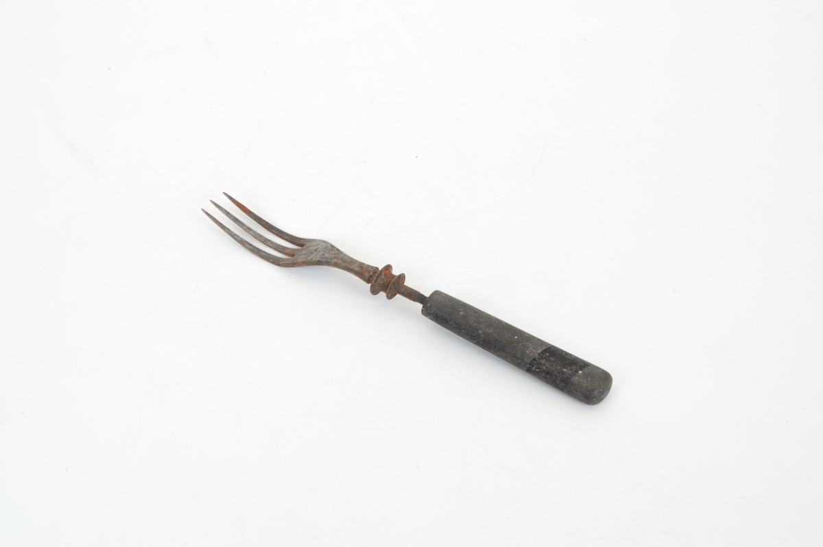 Form: Lang gaffel med tre tinder og treskaft. Stålet øverst på håndtaket har to riller.
