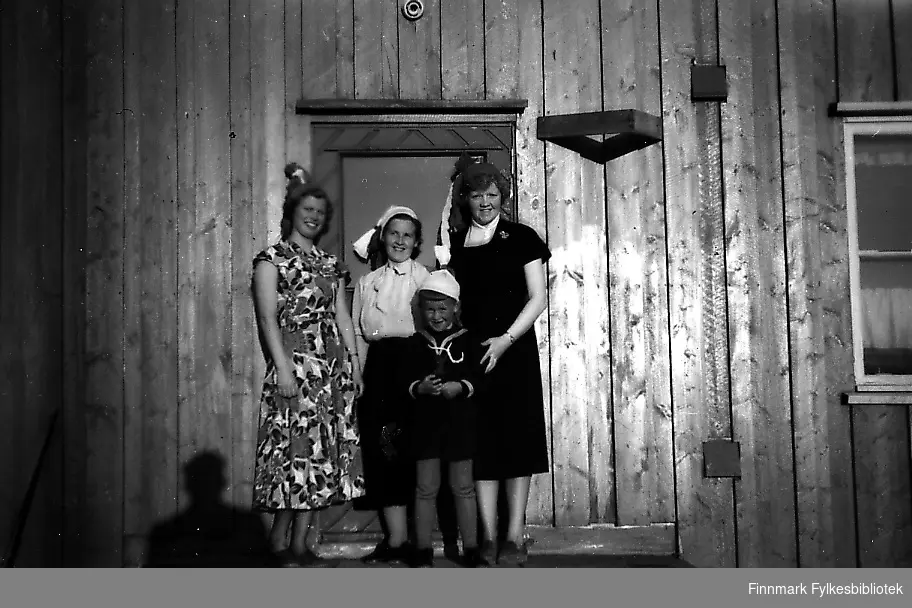 Tre damer og en gutt står på trappa. Kvinnene har kjoler på seg, det er 17.mai og dagen er solig og fin. Gutten heter Bjørn Ottar Betten og er kled i matroseskjorte og knebukser. Kvinnene fra venstre: frøken Birkeland, Gjerdrud Betten og frøken Bye. Alle tre jobbet som lærerinner på Seida skole i 1955.