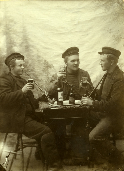 Skipper og reder i Alsvåg, Øksnes, Nordahl Pedersen (1877-1938) fotografert i fotostudio i Tromsø sammen med to andre unge menn.