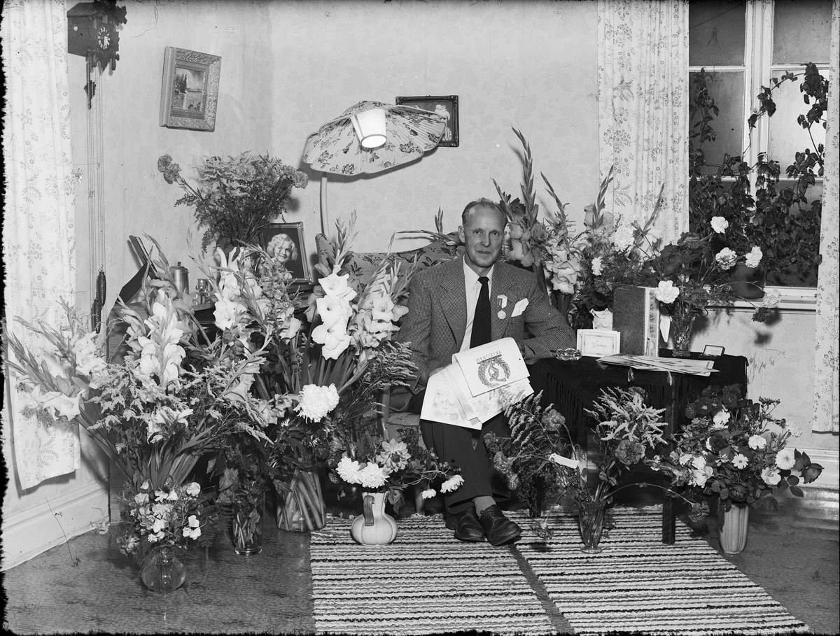 Man i hemmiljö, omgiven av blommor, firar 50-årsdag, Östhammar, Uppland