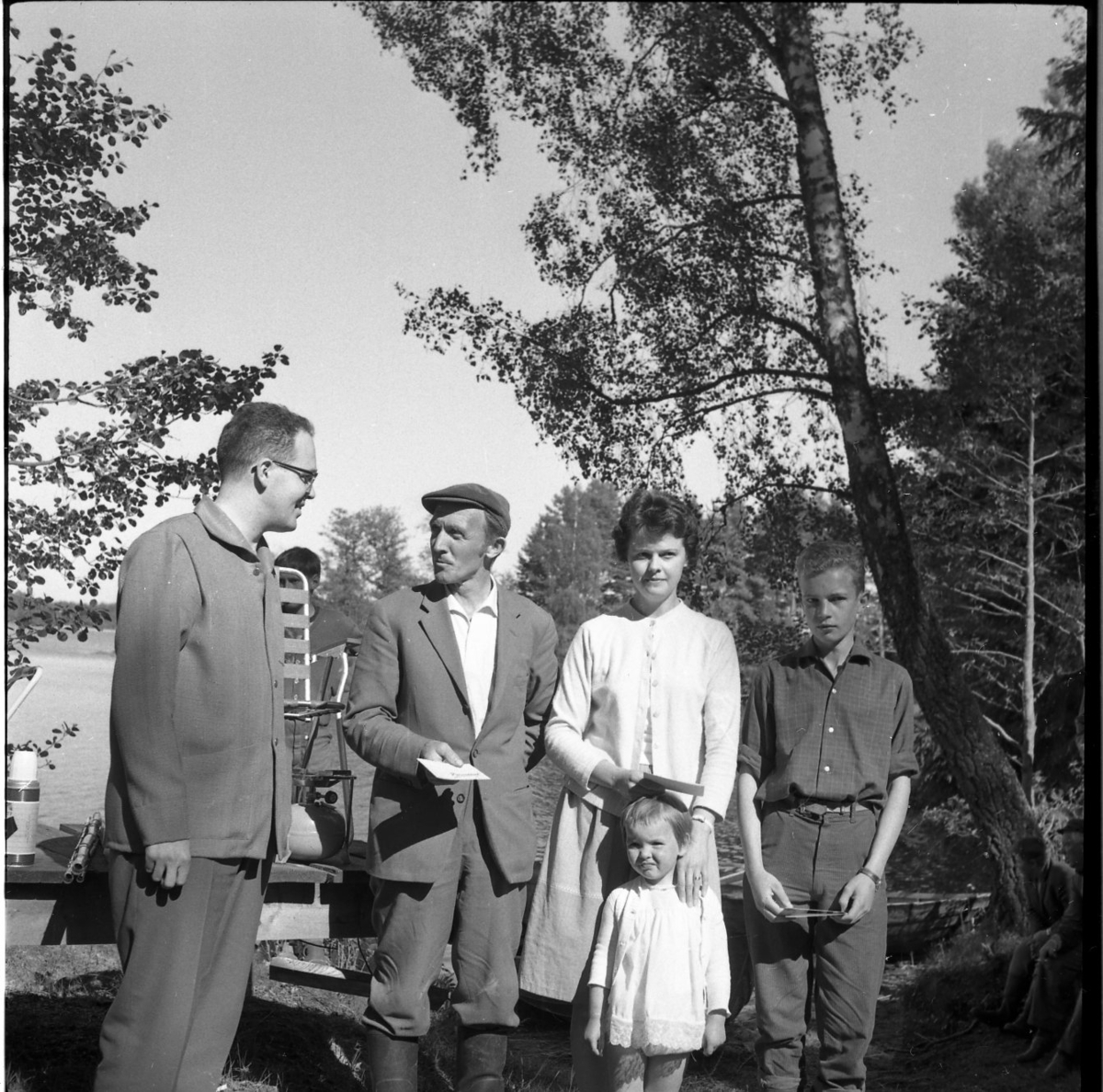 En man, en kvinna med en liten flicka samt en pojke står uppställda för fotografen med ett presentkort? i händerna. Till vänster står en man och samtalar med dem. De är från vänster Ingemar Lago, Ivar Adolfsson och Birgitta Berglund.