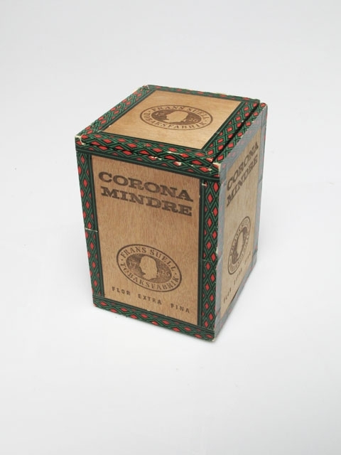 Askar för 25 cigarrer av märket "Corona Mindre", N:r 107. Denna cigarrtyp tillverkades 1939-1984 av Svenska Tobaksmonopolet (STM) (nuvarande Swedish Match). Askarna är tillverkade i trä och har följande beteckningar: Ask 1: "Corona Mindre" med STMs logotyp samt en prislapp på 80 öre för en cigarr och 20 kr för full ask. Ask 2: "Corona Mindre" samt "Frans Suell Tobaksfabrik 1726". Ask 3: "Corona Mindre" med STMs logotyp samt en prislapp på 1,10 kr för en cigarr och 27,50 kr för full ask.