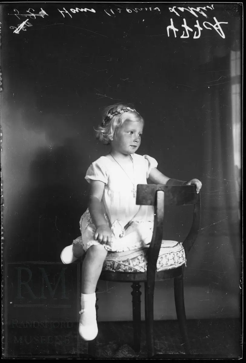 Portrett av ei jente som sitter på en stol..