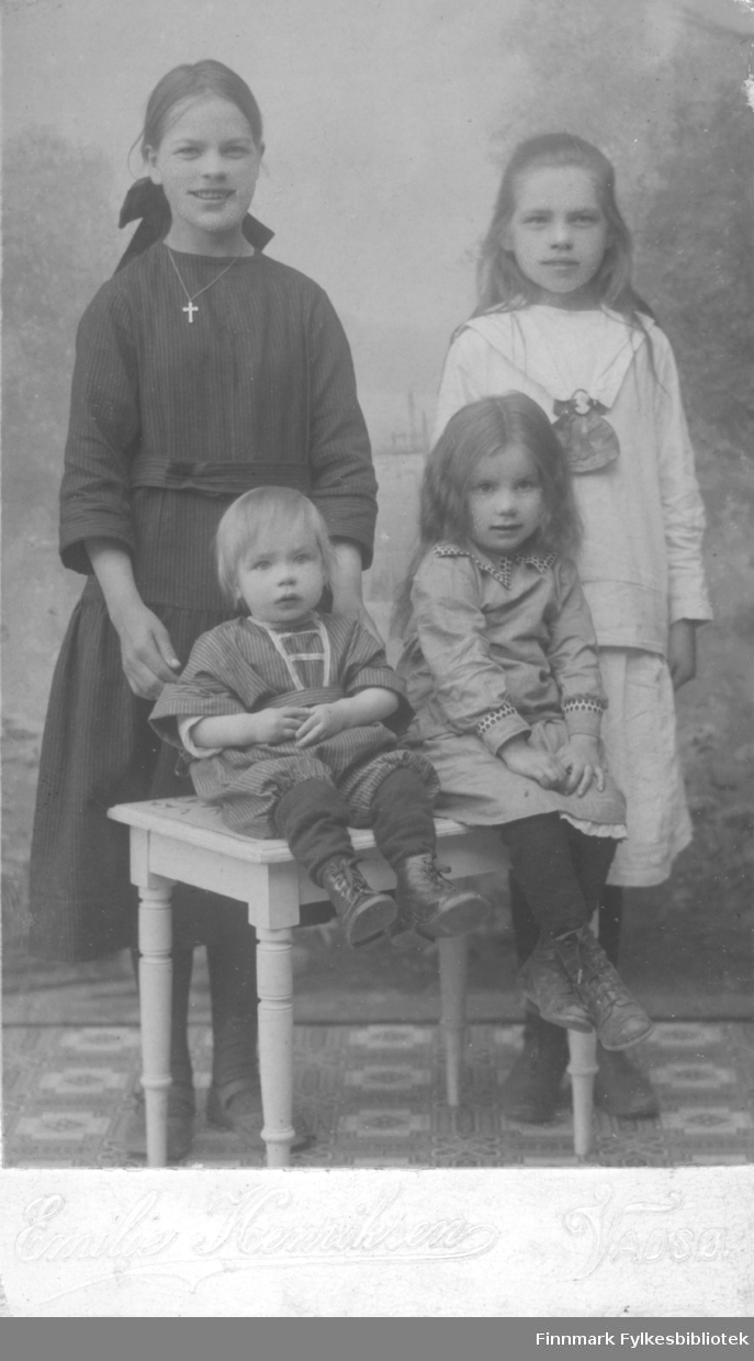 Et fint bilde av fire barn fotografert i fotoatelier til Emilie Henriksen, Vadsø. Emilie Hendriksen (1877 -1954) var en norsk fotograf som hadde virkested Vadsø i perioden 1905 til ca. 1911. 
