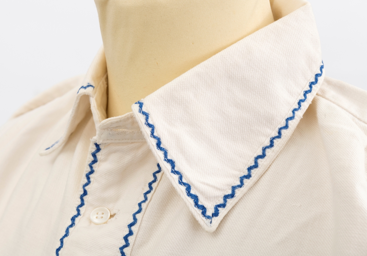 Skjorte med blå kroklisser på ermer og bryst.