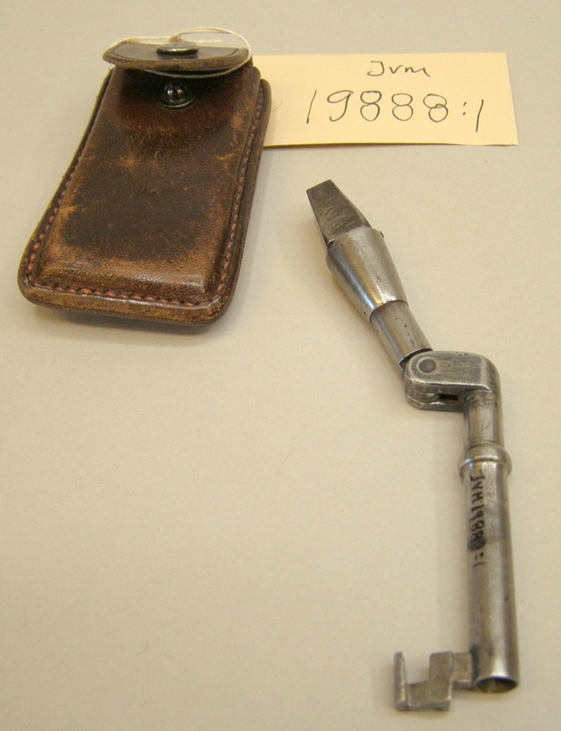 Vagns- och kontrollåsnyckel av metall med läderfodral.
Nyckeln har tredubbel funktion: I ena änden en så kallad fyrkantsnyckel. Själva fyrkantsdelen är i form av en bits som går att plocka ut. Då bildas en vagnsnyckel som det går att att öppna vagnsdörrar på tåg med. I andra änden en nyckel som liknar en så kallad k-nyckel, kontrollåsnyckel. Okänt till vad för typ av lås nyckeln kan passa. Nyckeln har förvarats i ett särskilt fodral av brunt läder med lock som öppnas och stängs med tryckknapp.
