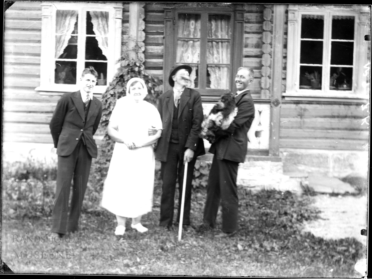 En gruppe på fire stående utenfor et hus.