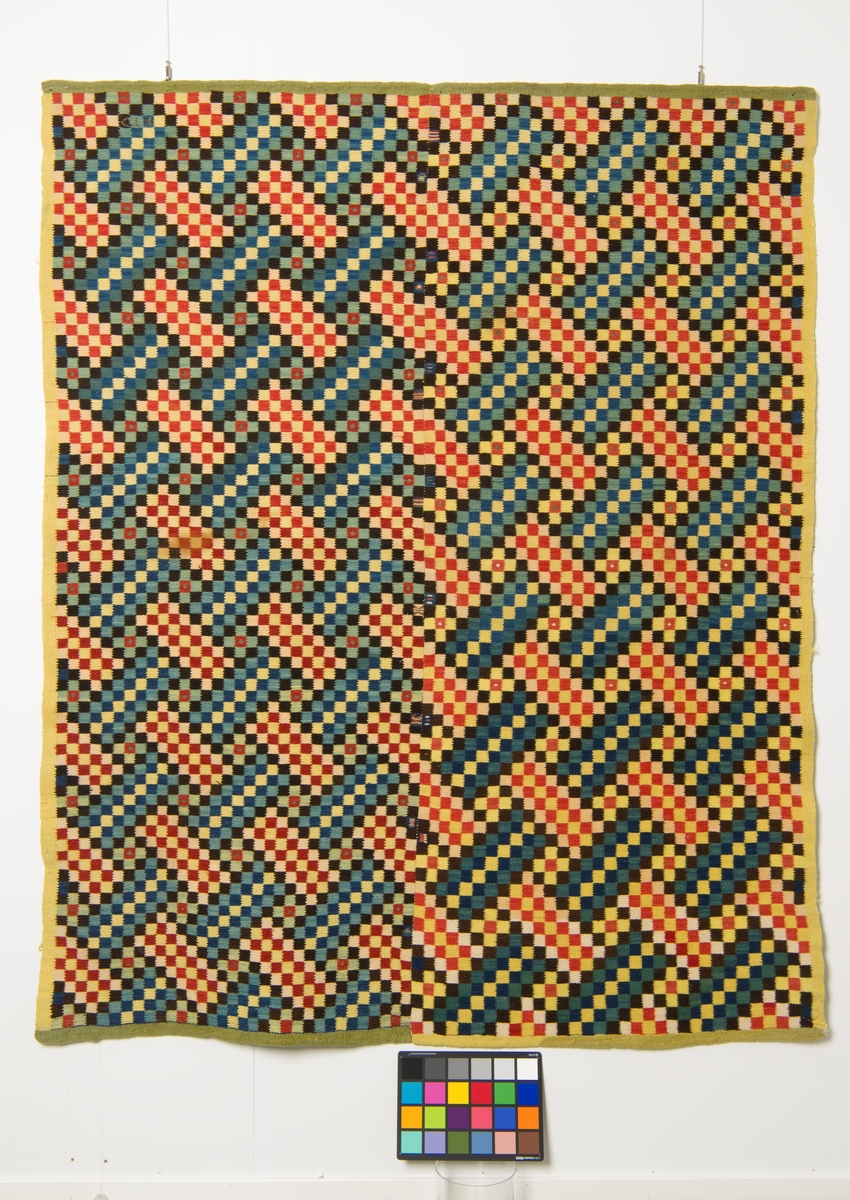 Vevet åkle med flerfarget sikksakk-mønster dannet av kuber, med gul og grønn innramming.