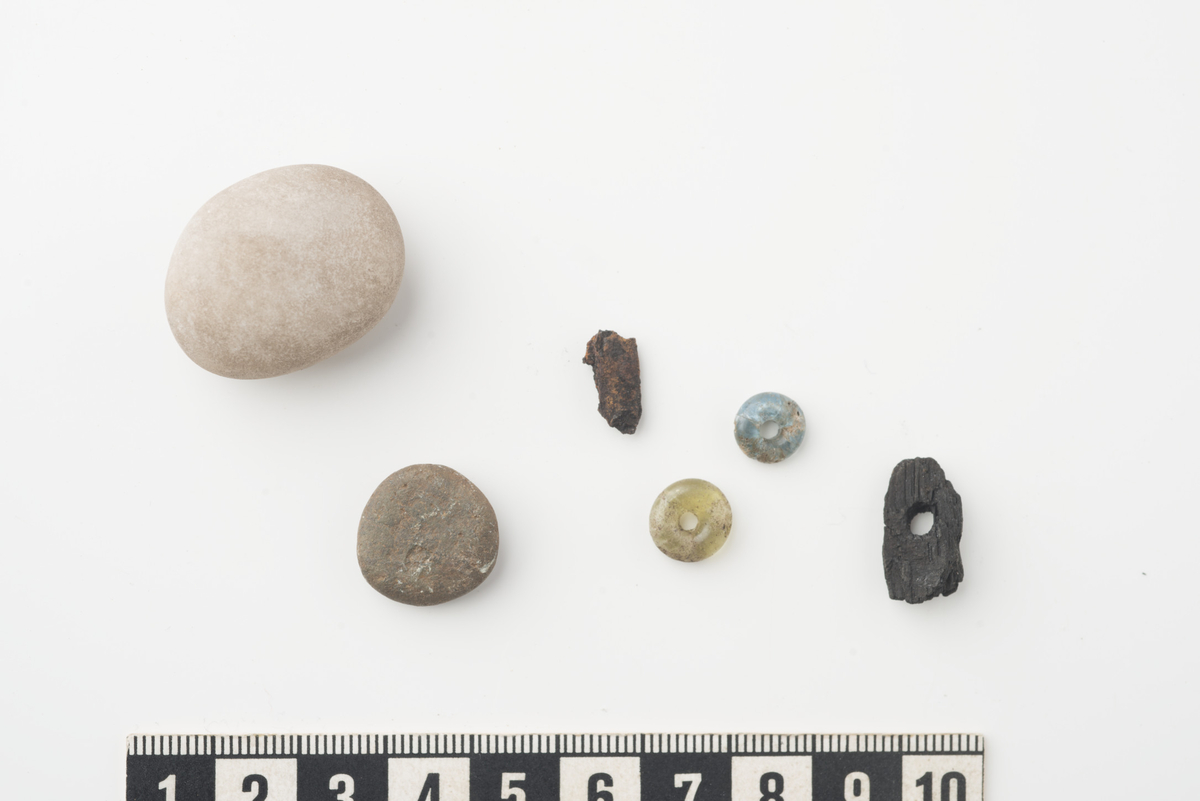 To små runde steiner. Kosesteiner. En av kvarts (12,8 gr, st.l. 28 mm, st.b. 22 mm, st.h. 14 mm). En av bergart (2,2 gr, st.l. 16 mm, st.b. 16 mm, st.h. 6 mm).

