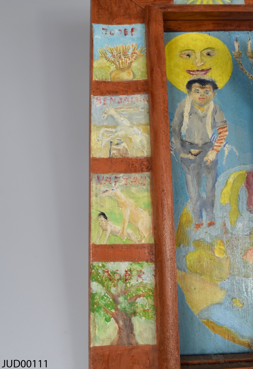 Tavla, bemålat trä med en bemålad ram. Stor tredimensionell bemålad träfigur i mitten av tavlan föreställande judisk man med tefillin och tallit. Bilderna som är målade runt om på ramen föreställer judiska stamfäder. På baksidan finns signaturen ”Albert Mankovitz -99”.