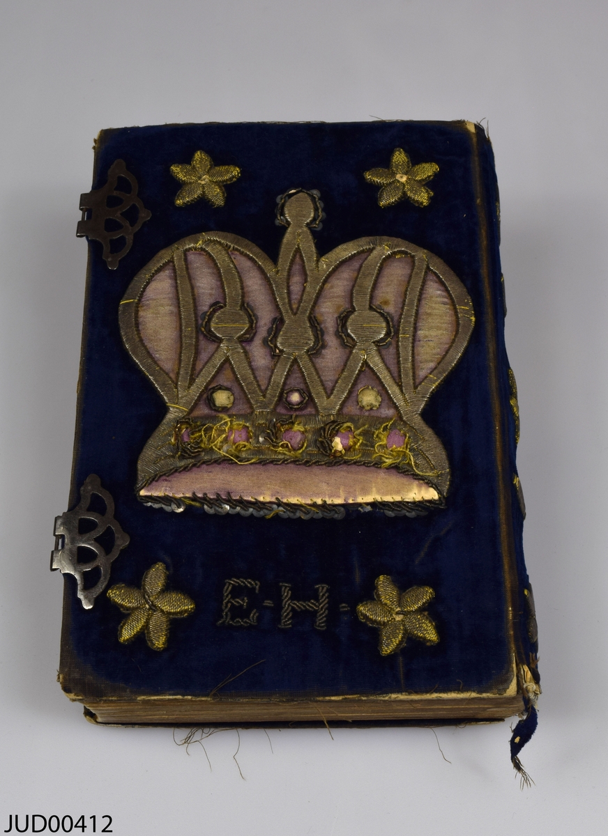Siddur med pike avot. Boken har ett sammetsomslag med silvertrådsbroderade blommor, en krona och initialerna EH. Två spännen på sidan för att hålla ihop boken. Boken är tryckt på papper i Prag 1867 och är skriven på hebreiska och tyska.