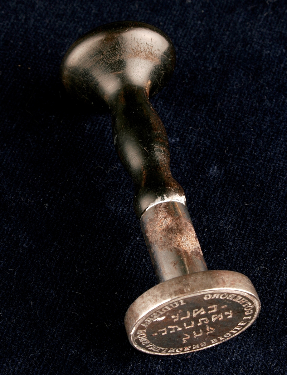 Stämpel tillverkad av silver, med trähandtag. Sigilltext: Iudiska församlingens sigill i Götheborg, samt hebreisk text.