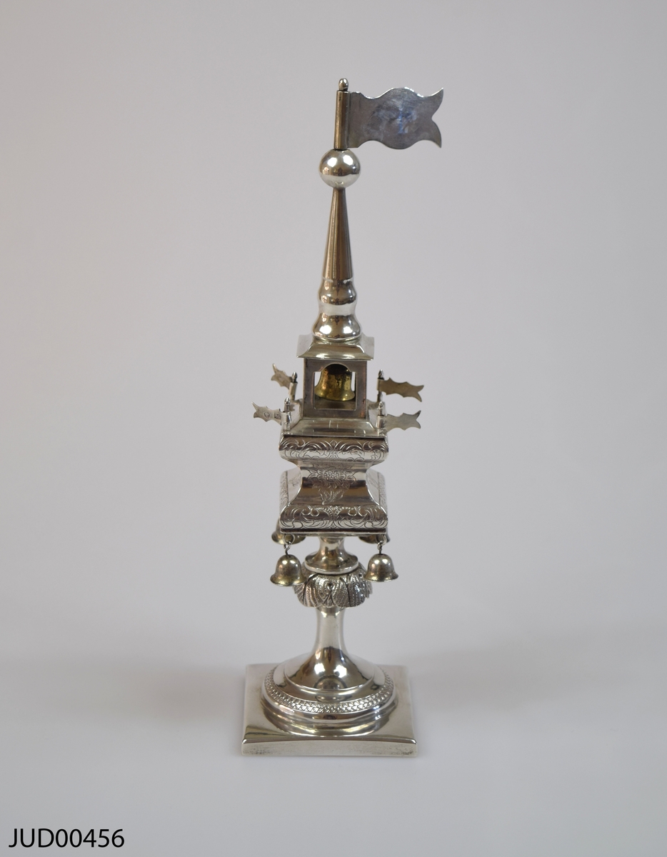Kryddbössa, tillverkad av silver, i form av ett torn. Dekorerad med klockor och flaggor.