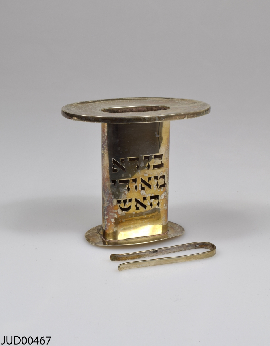 Silverljushållare för havdalaljus. Genombruten dekor i form av hebreisk text. Stämpel i botten med texten ”Made in Israel”.