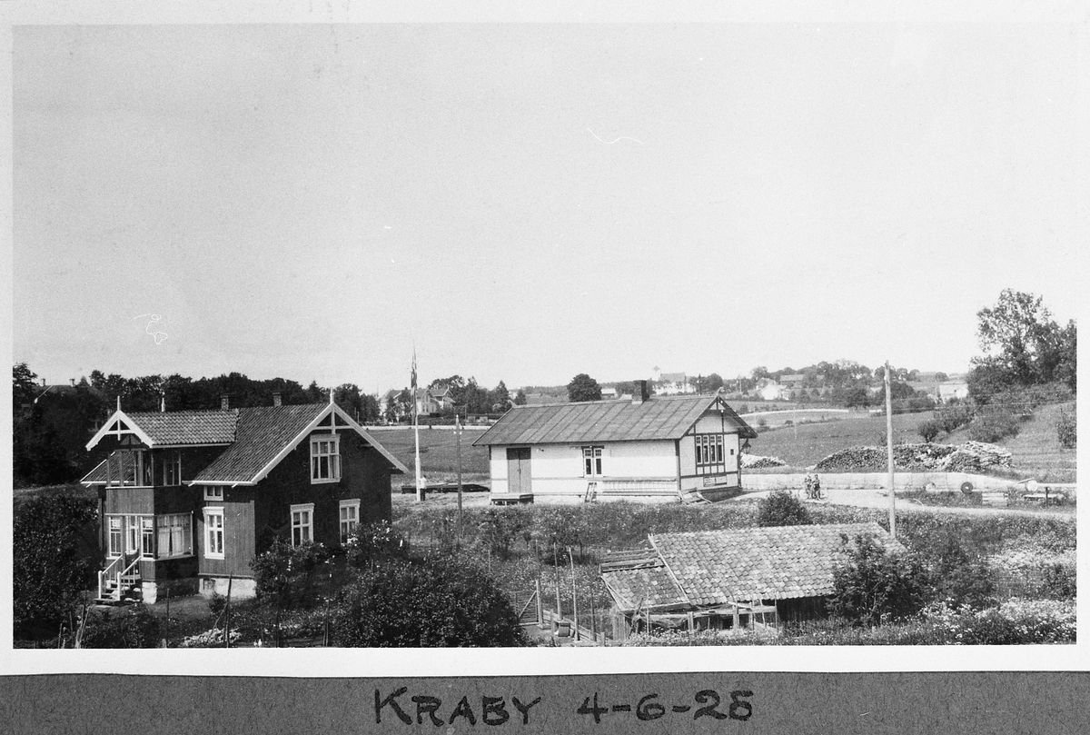 Kraby stasjon på Skreiabanen juni 1925. Det mørke huset er stasjonsmesterrens bolig, det lyse er stasjonsbygningen.