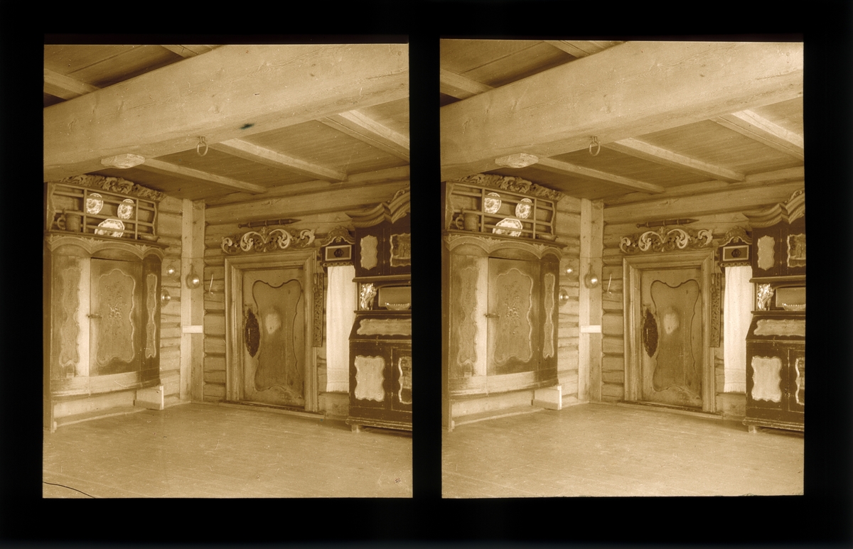 Stue. Møblert med malte skap. Dekorative treutskjæringer over døren. Tilhører Arkitekt Hans Grendahls samling av stereobilder.