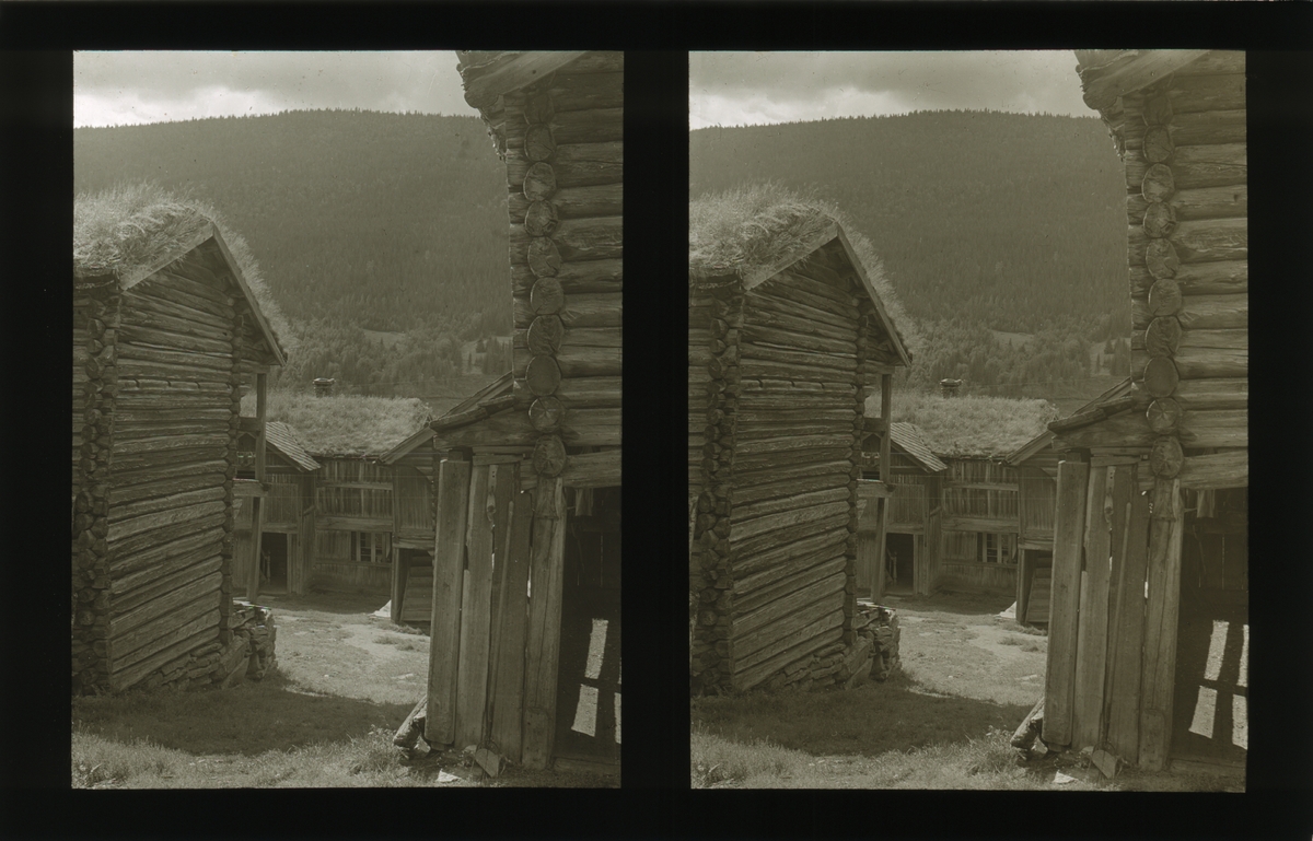 Innsyn på tunet, mellom to laftede tømmerbygninger. Tilhører Arkitekt Hans Grendahls samling av stereobilder.