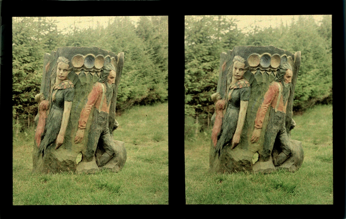 Bakside av kubbestol med utskjæringer som viser en mann og kvinne med et barn. Tilhører Arkitekt Hans Grendahls samling av stereobilder.