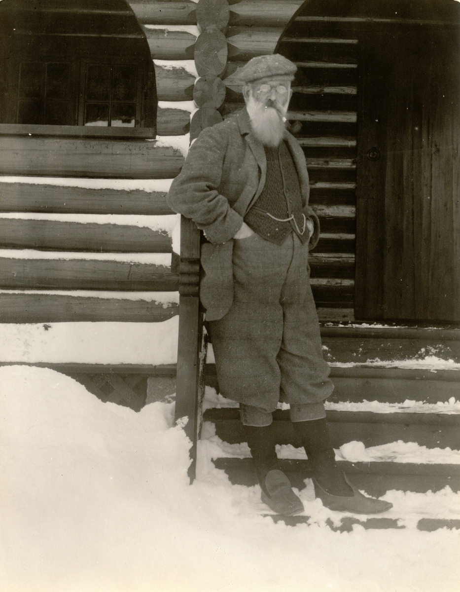 Hoffjegermester Thomas Fearnley, æresmedlem av skiklubben Fram, på trappen til klubbens skihytte ved Harestuvannet i Lunner. Fotografert i desember 1909 i forbindelse med klubbens 20-års jubileum.