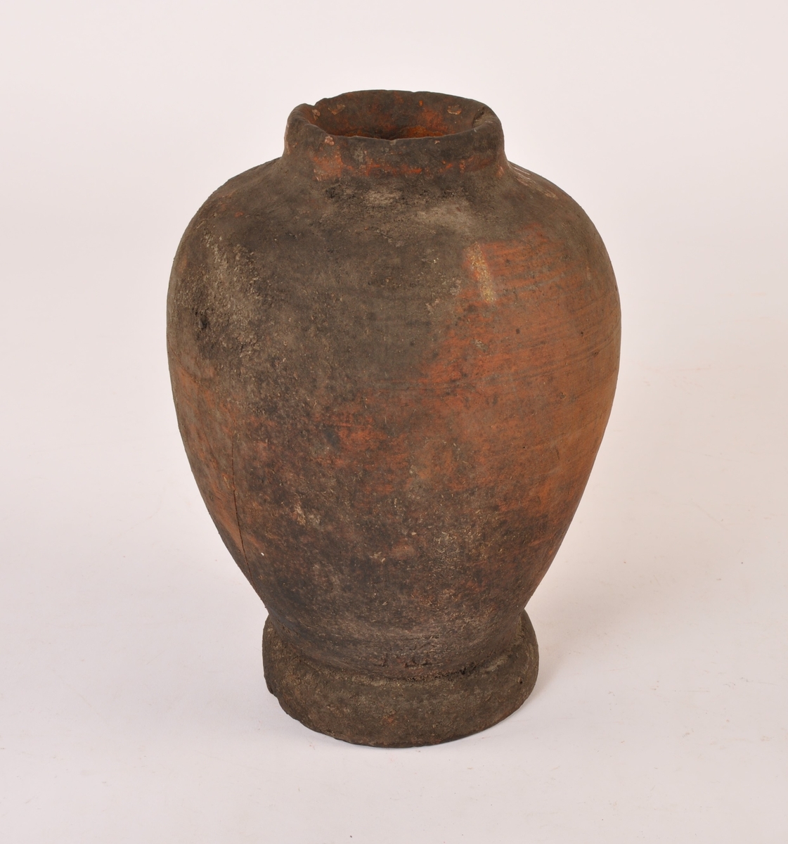 Dreid krukke i keramikk med fotrand og munningsrand. Sylinderformet med bredere form opp mot munningen. Rester av glasur på utsiden. Glasert innside.